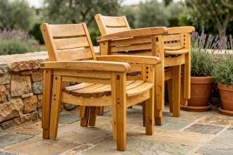 Fauteuil de jardin en teck empilable posé sur une terrasse en pierre naturelle avec plusieurs chaises empilées en arrière-plan